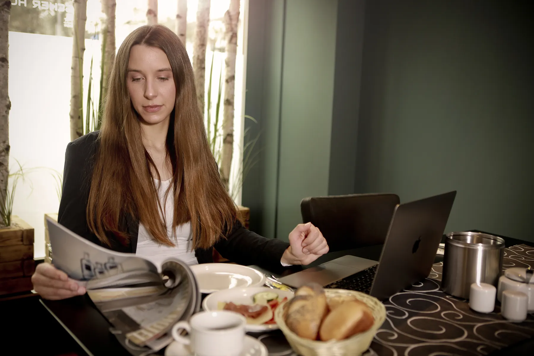 Gast beim Frühstück mit Zeitung und Laptop