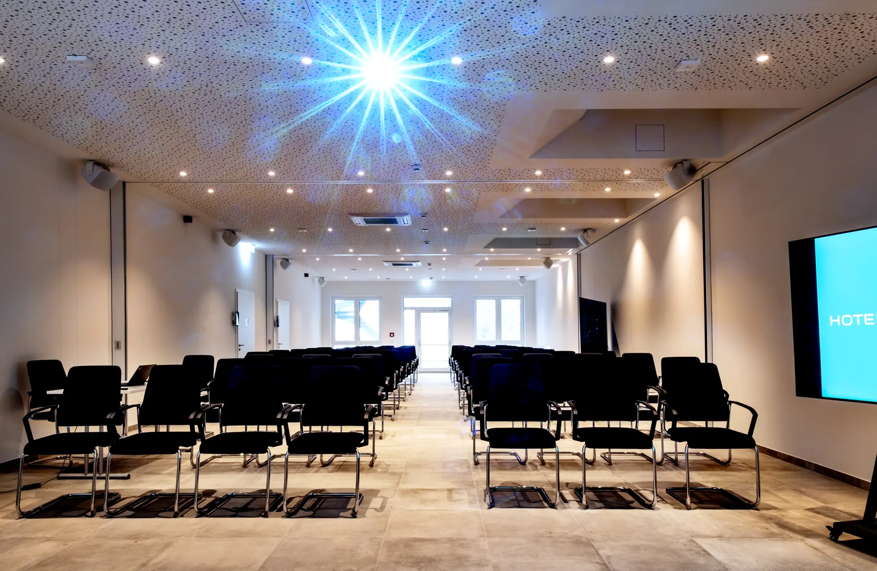 Großer Tagungsraum mit Stuhlreihen und Leinwand